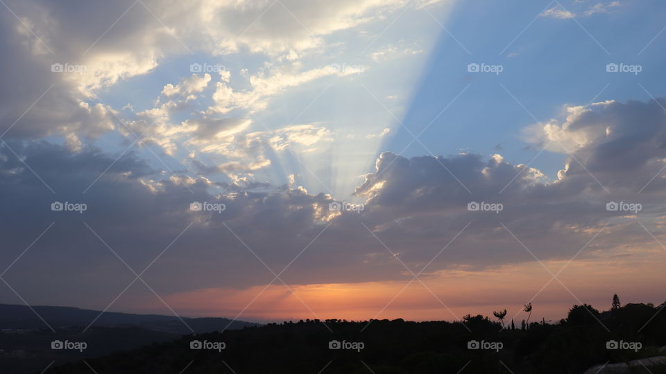 Orange and blue sky with grey clouds and sunlight 