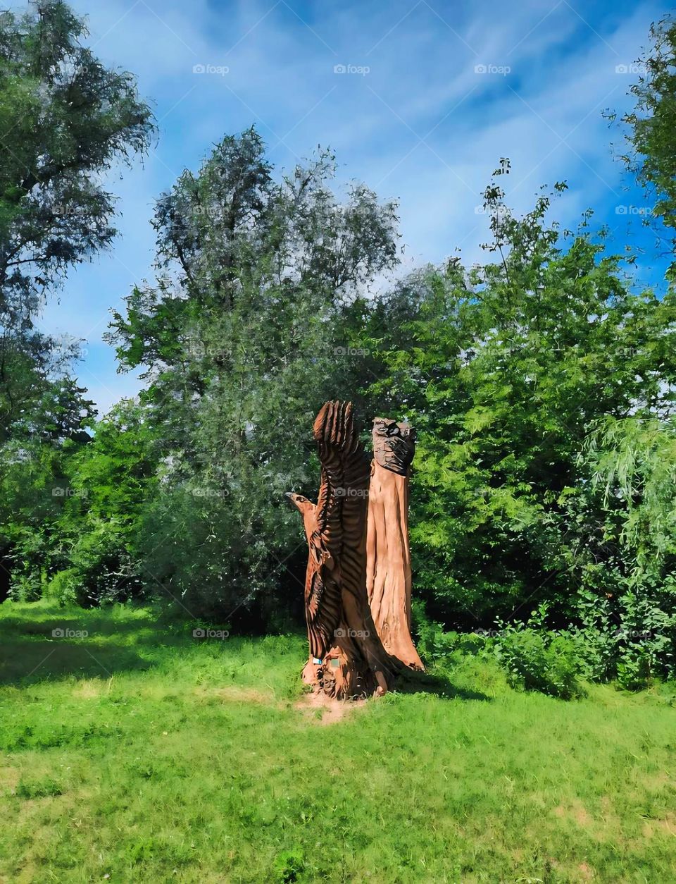 "Wood Carved Sculpture of an Eagle in a Lush Forest Clearing"