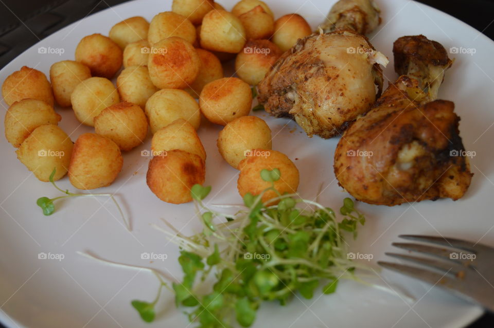 A delicious dish. Chicken legs with baked potato balls and salad with fresh cress