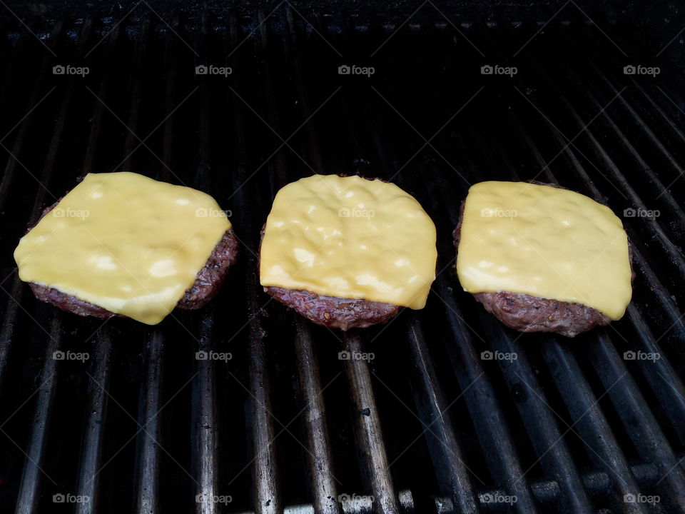Three cheese burgers on the grill