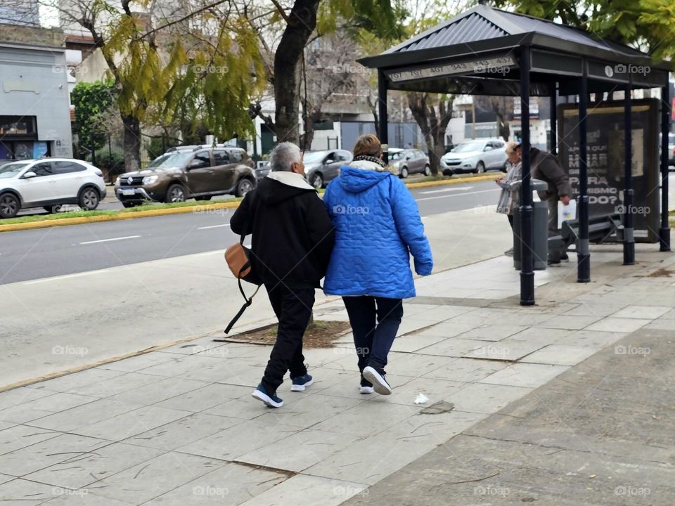 Two women,  arm in arm, walking on the sidewalk. Sisters, friends, companions for life.