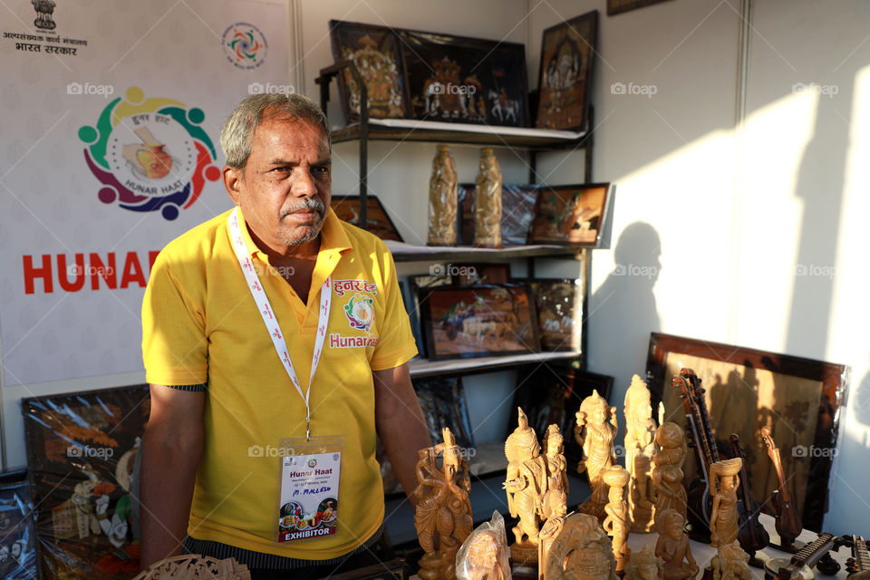 A seller selling wooden art and craft items at the Hunar Haat, New Delhi, India