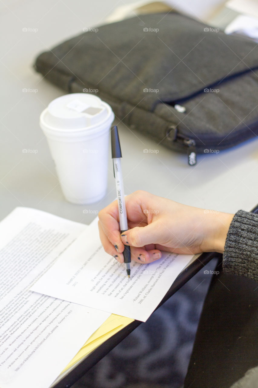 A woman writes in a book and takes notes at a desk