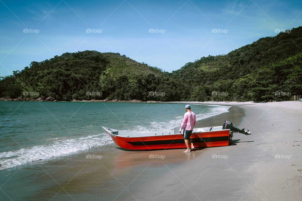 Sailor with his boat on the beach, preparing to cross the sea to get Supplies, at Ubatuba, Brasil.