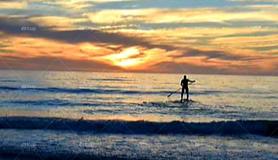 A sunset paddle boarder has the best view