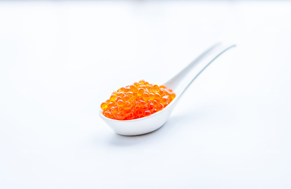 Red salmon caviar in a light blurry spoon with copy space.