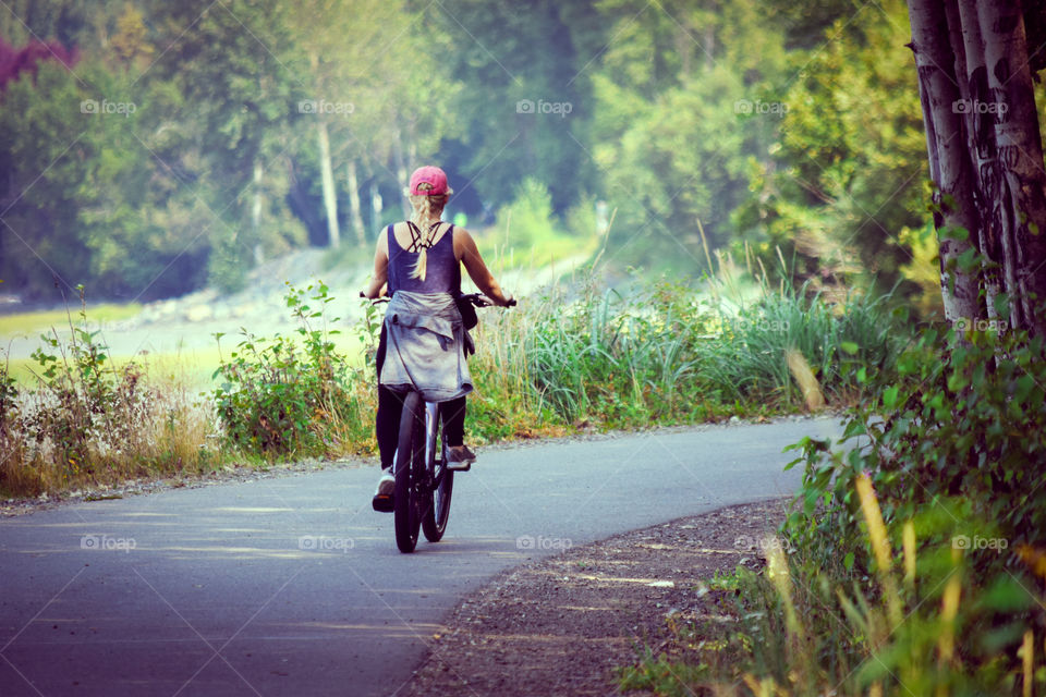 A woman biking into the trail (rule of thirds, leading lines, framing the subject).