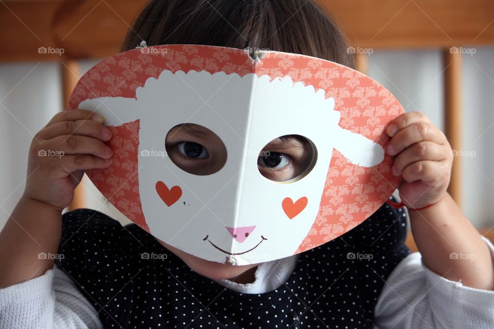 Cute little girl is peeking through the holes in a book