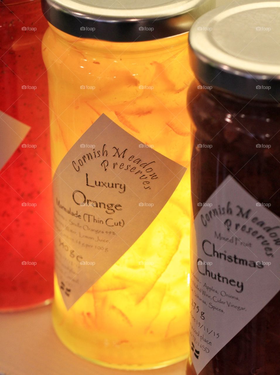 Luminous Marmalade. A jar of marmalade with a glow from artificial light sitting on the store shelf amongst a row of preserves.