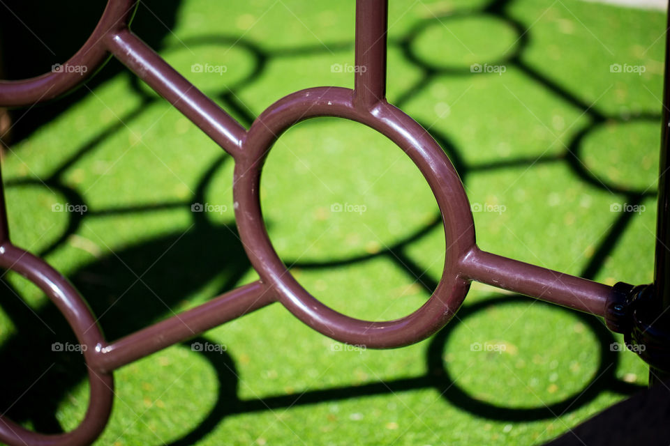 Simple lines and shapes on the playground with climbing rings and shadows on the green grass