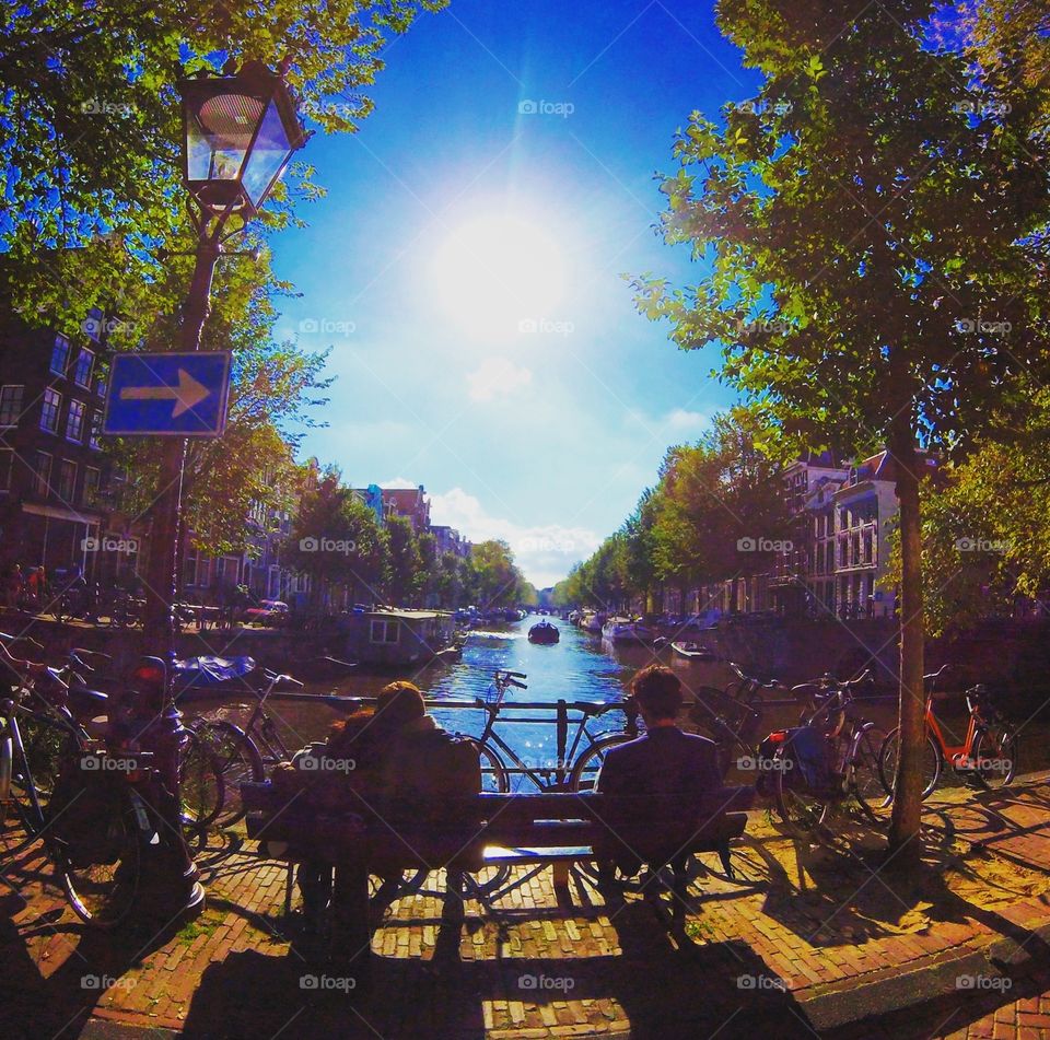 Sunny afternoon in Amsterdam. Walking along the canals, I spotted a couple and a single man sitting on the same bench. Which one would you rather be? 
