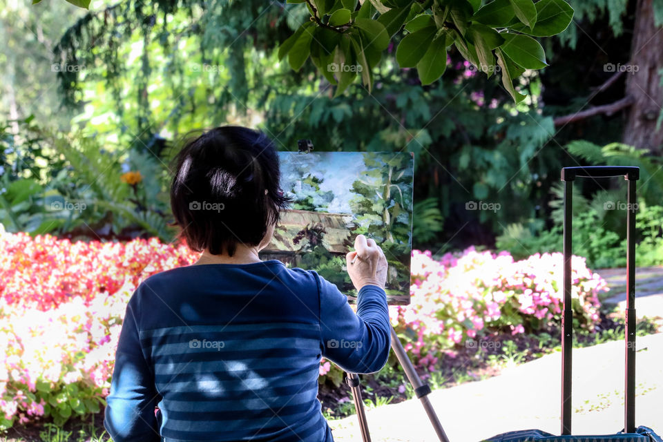 Senior woman is painting a beautiful landscape in the park