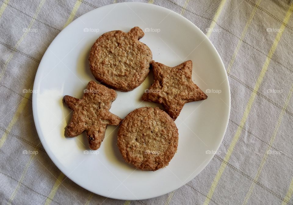 Matzo meal cookies with star, round shapes and white round plate background.