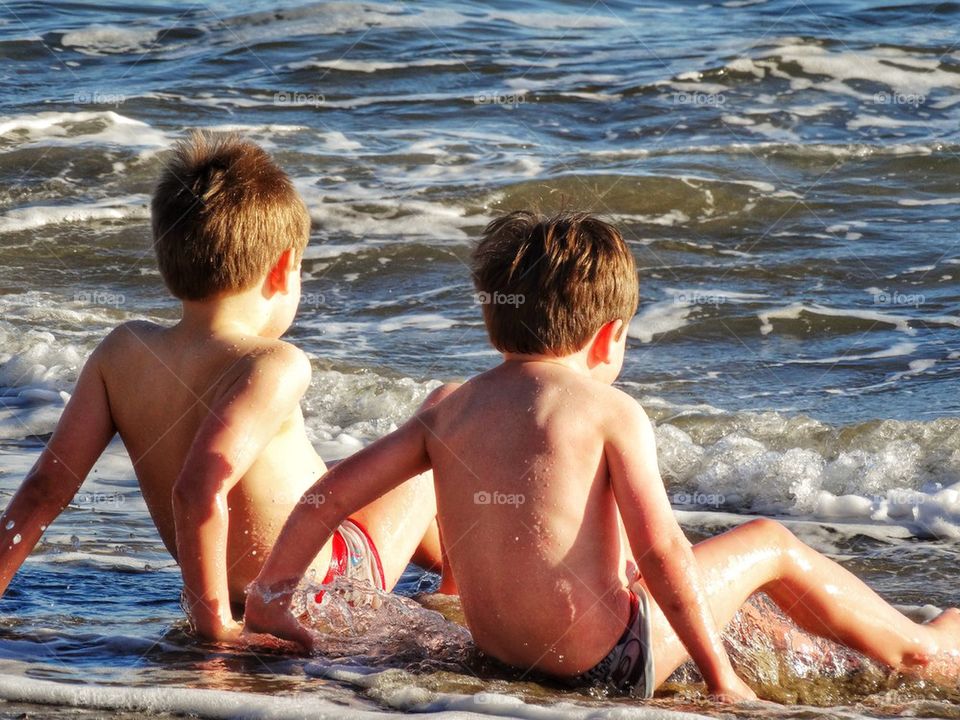 Two Brothers Playing Tag With Ocean Waves. Young Boys At The Beach
