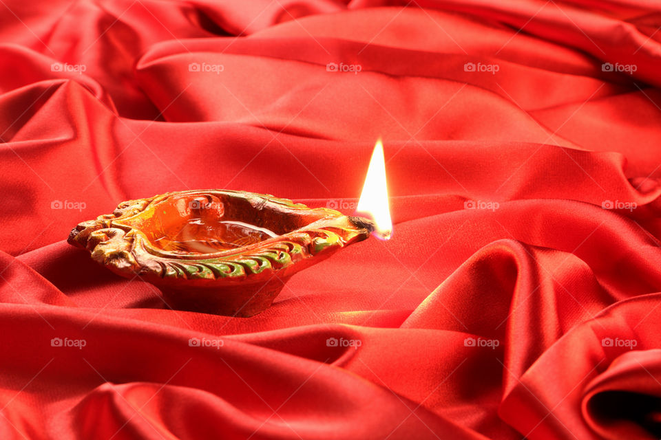 Beautiful traditional handmade Diwali diya oil lamp on red satin background