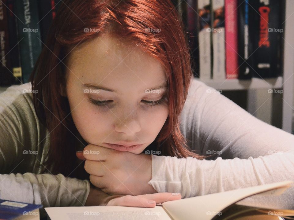 Small girl reading book in house