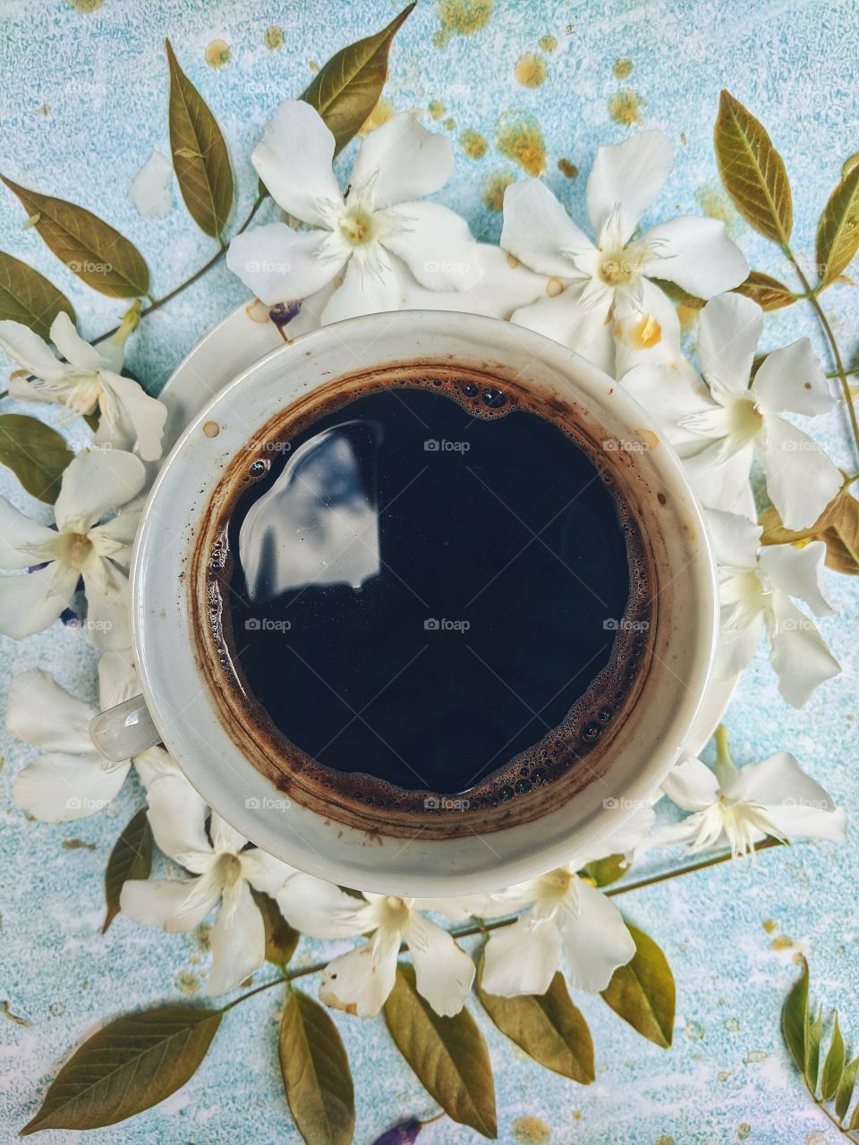 Background of a cup of hot coffee on the table with beautiful flowers close-up. Top view.