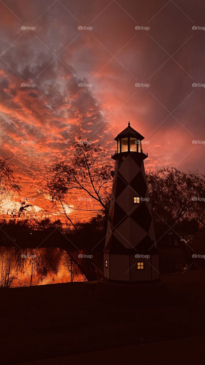 The lighthouse lights are on and the sky lights are whay brighter than the tower. The end is near the sky darkens Night is on the way.