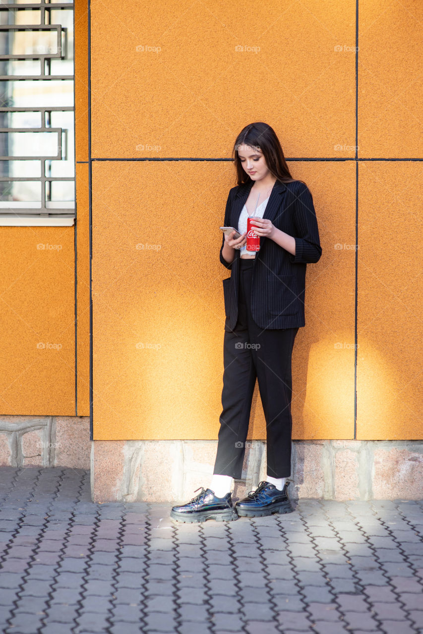 Young girl drinks Coca-Cola and surfs in smartphone