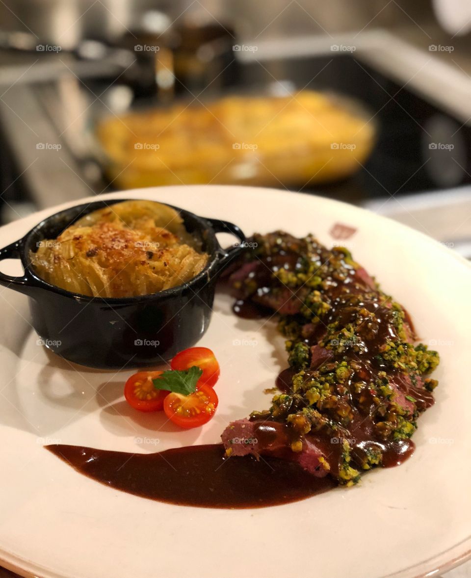 Lambloin served with boulangere potatoes, redwine sauce with a pistachio and fresh herbs-pesto on top