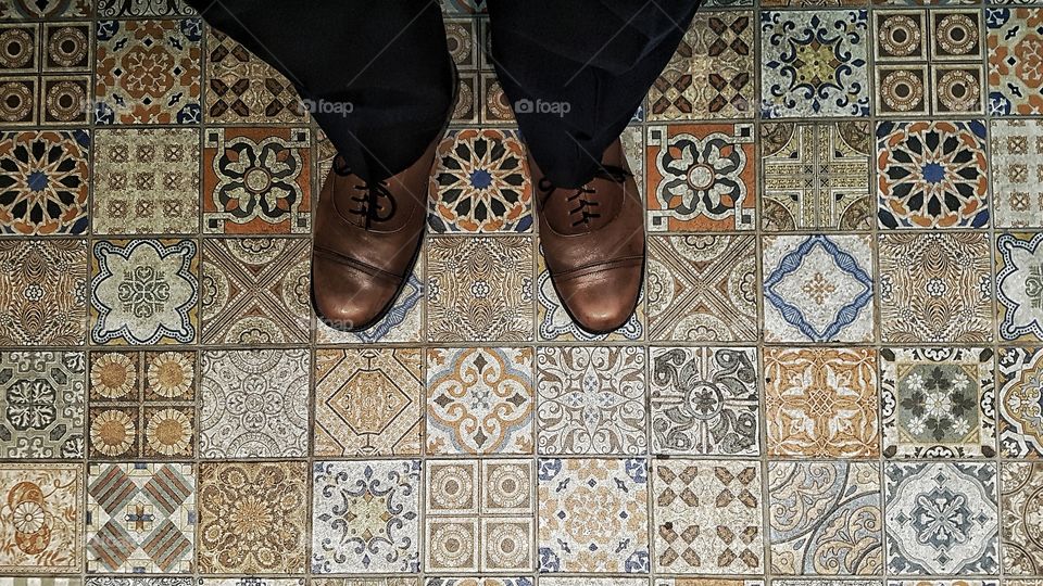 top down view of feet on geometric square ceramic floor tiles