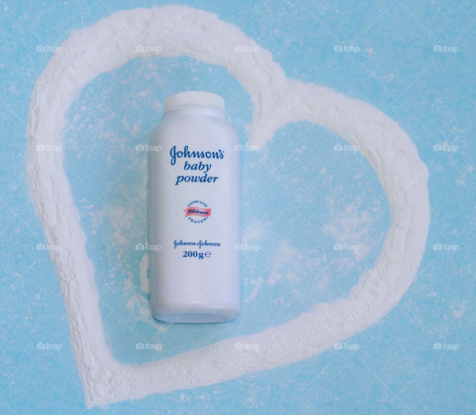 Johnson’s Baby Powder in a heart shaped out of talc on a pale blue background 