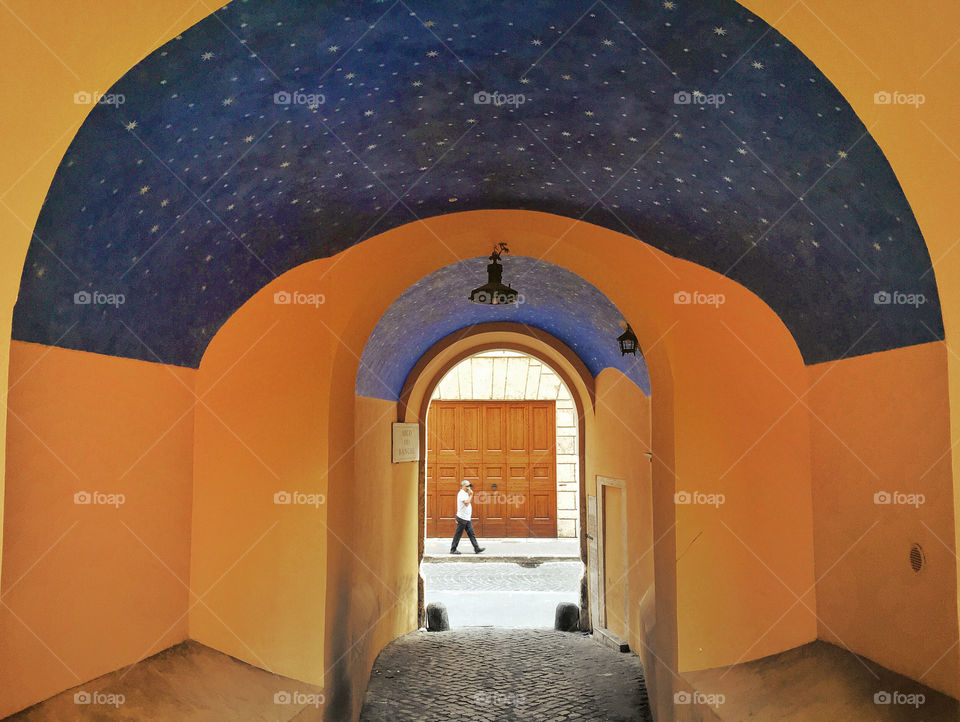 The pitoresque Arco dei banchi in Rome with its starred paint ceiling and a man walking