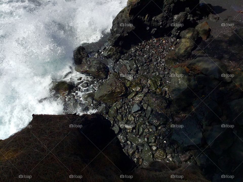 Wave hitting a black sand beach