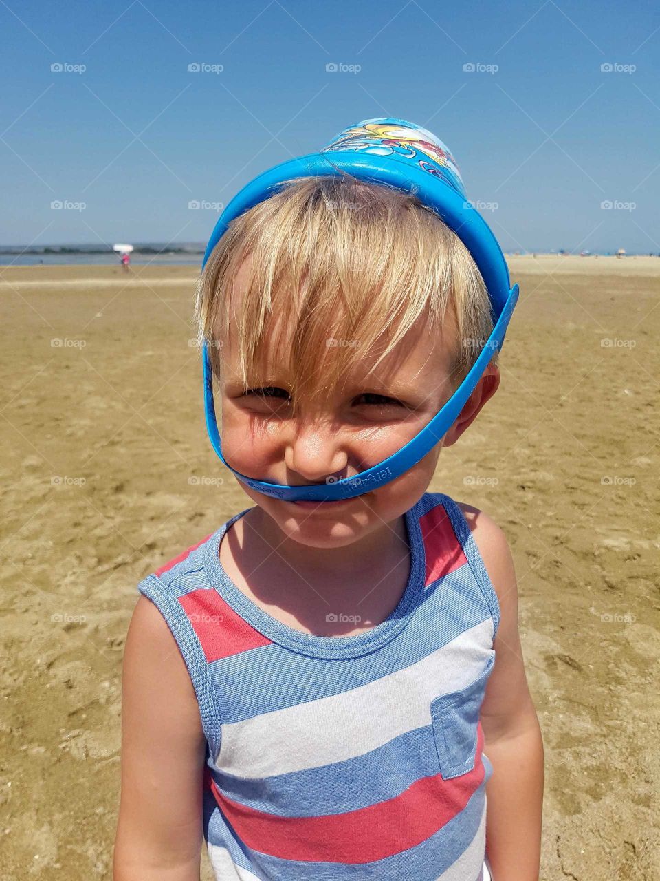 Little boy on beach with bucket on his head