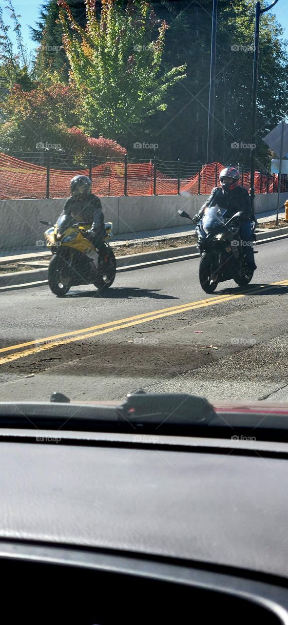 view from a car of two people riding motorcycles past an orange construction fence during rush hour in Oregon