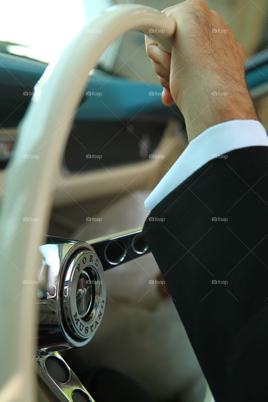 Man in suit driving a convertible Mustang