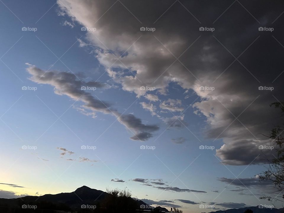 A sunset with mountains and storm clouds rolling in.