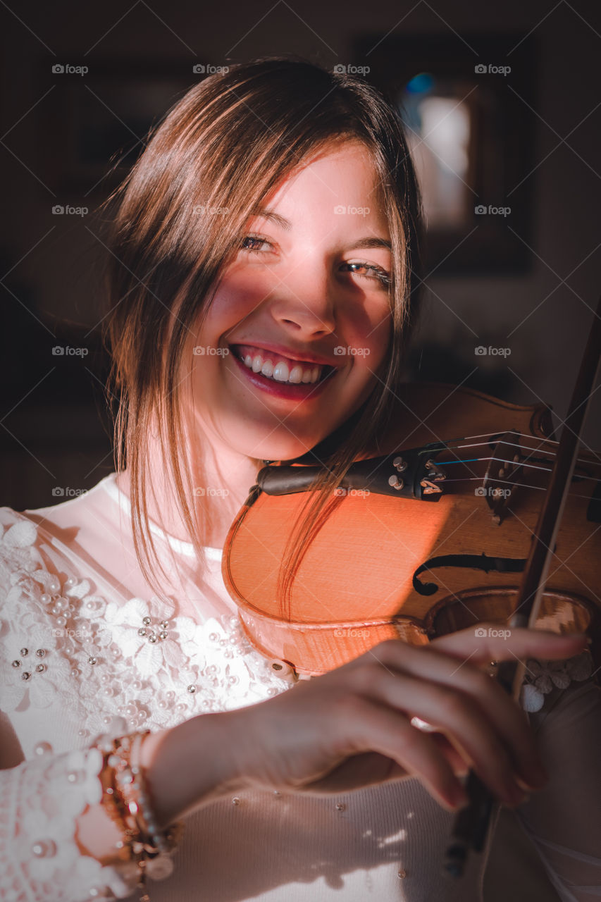 Girl holding a violin in the house