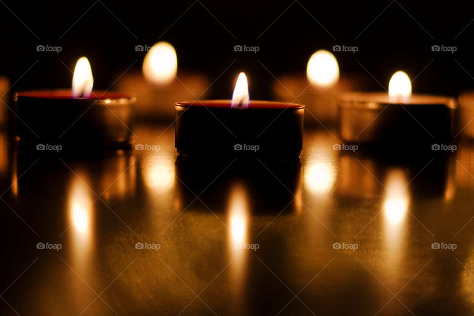 Burning candles with festive bokeh on a black background. Holiday concept. The concept of prayer and hope.