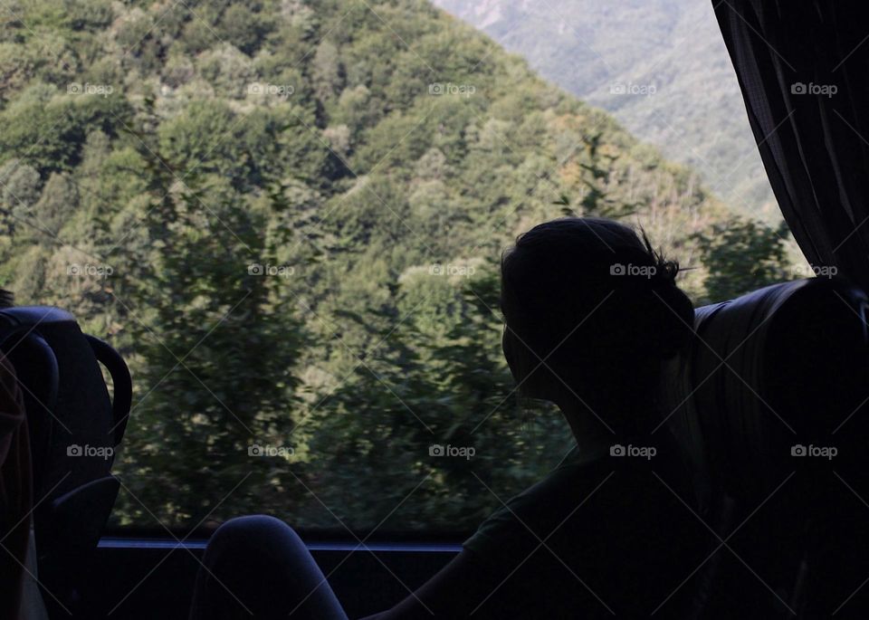 A young girl looking through the bus window and seeing hills