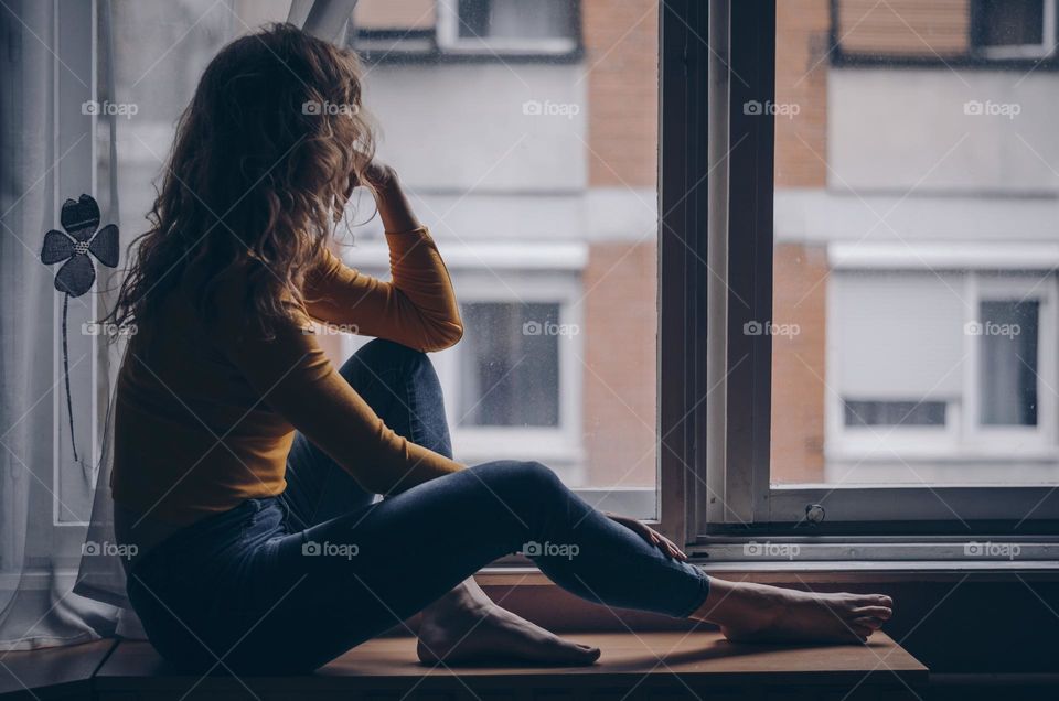 Young woman deep in thought sitting by the window