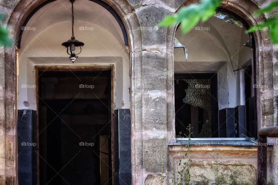 An old abandoned house with a semi-circular archway and broken windows