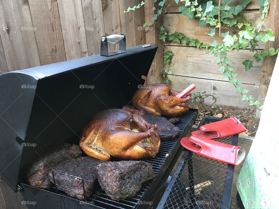 Turkeys and brisket cooking in a smoker