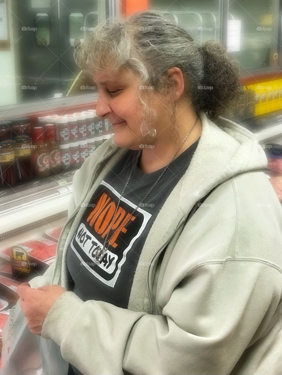 A woman looking at different packages of hamburger at the local supermarket. 