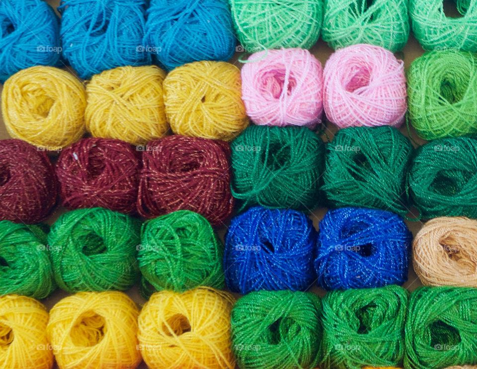 Many multicolored balls of yarn displayed in an upright box for sale on the street in San Miguel de Allende, Mexico.