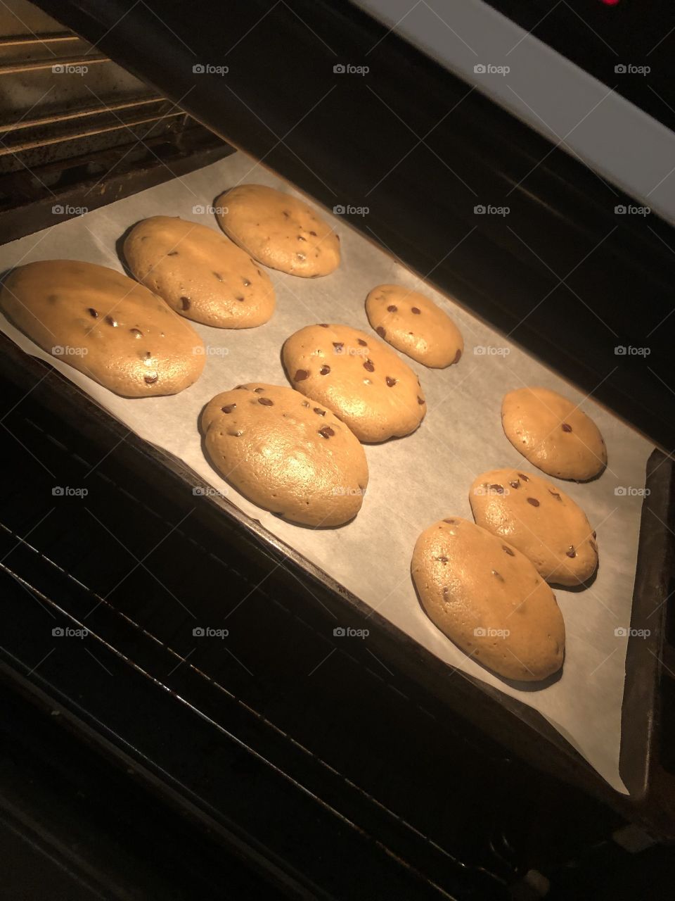 Chocolate chip cookies in the oven getting larger 