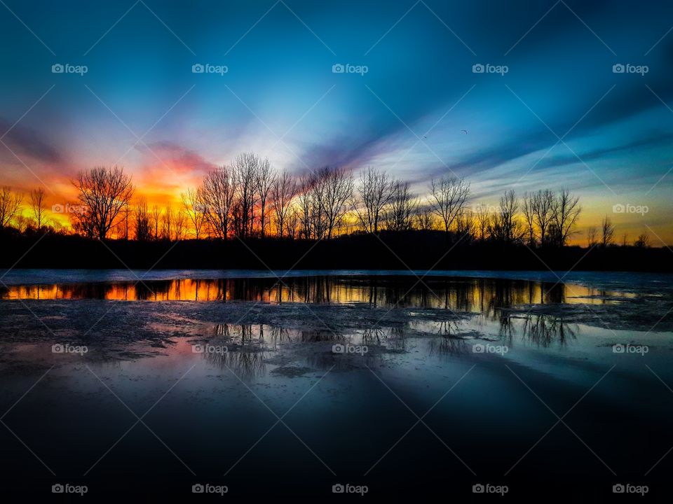 Vibrant winter sunset reflecting upon a pond.