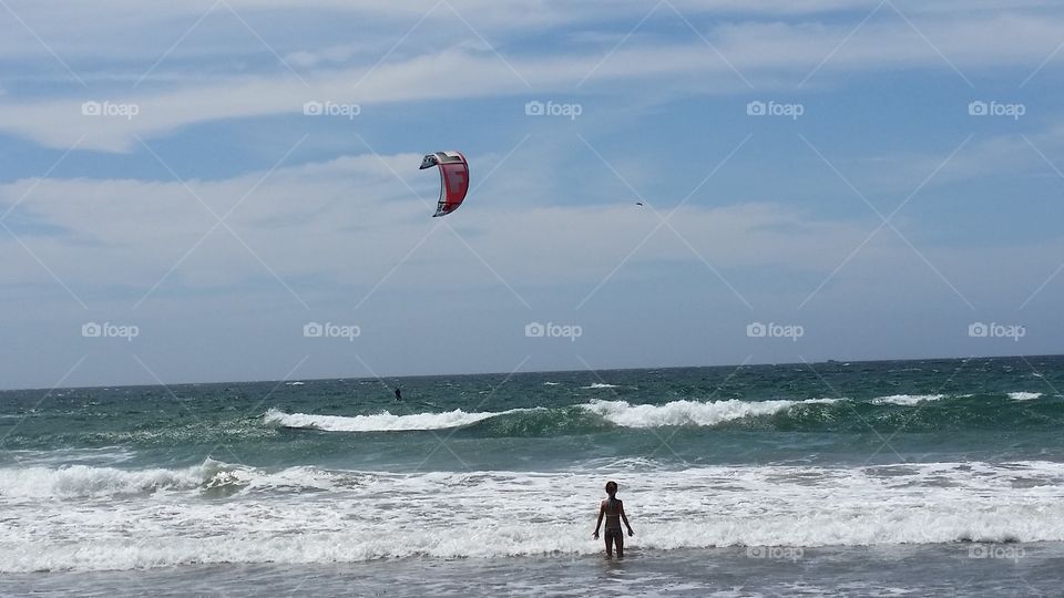 Kid watching a kite surfer in the ocean