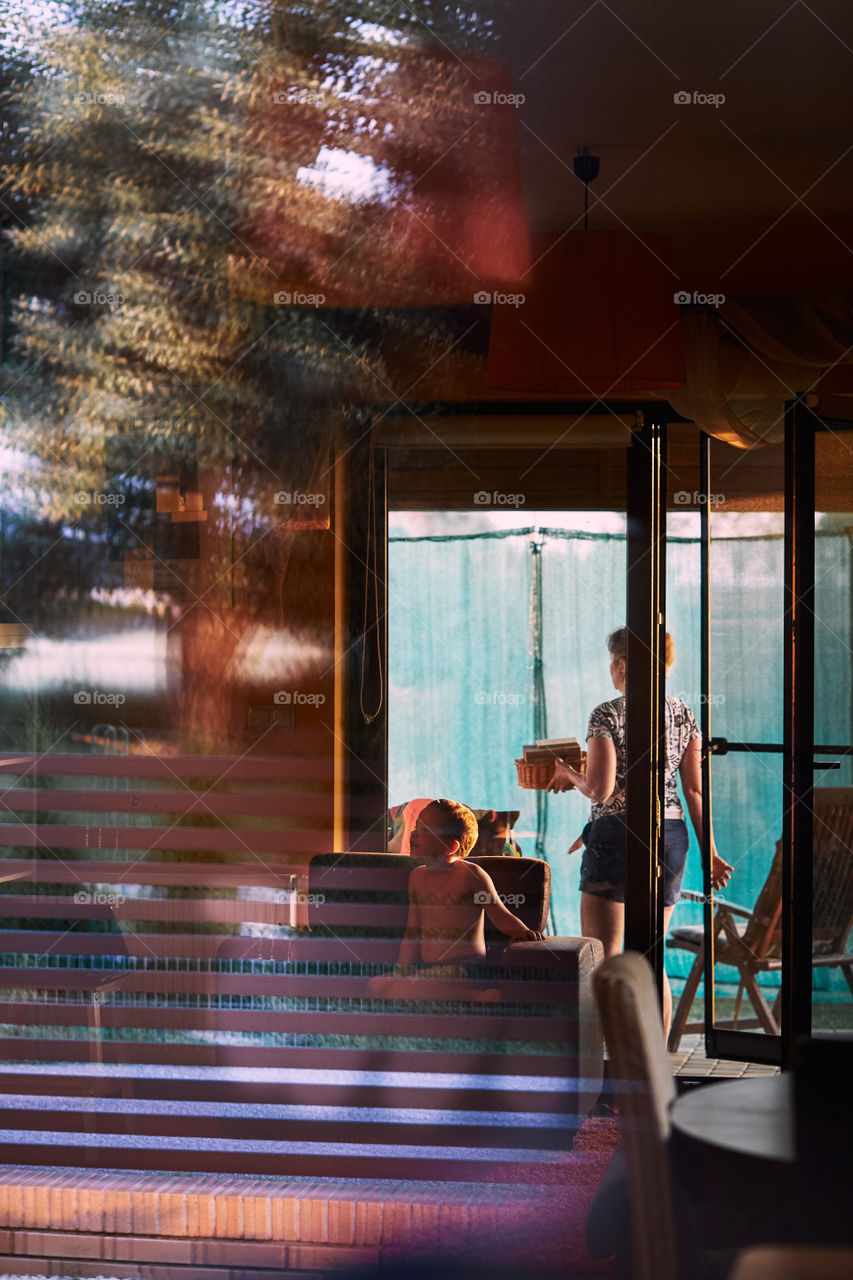 Interior of a house, family spending time at home. Reflections in a glass of window. Candid people, real moments, authentic situations