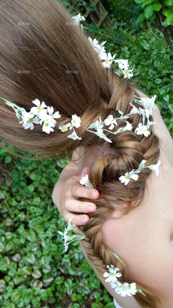 long light brown hair weaved into a fish tail braid , plaited with white snowflake lambs flowers