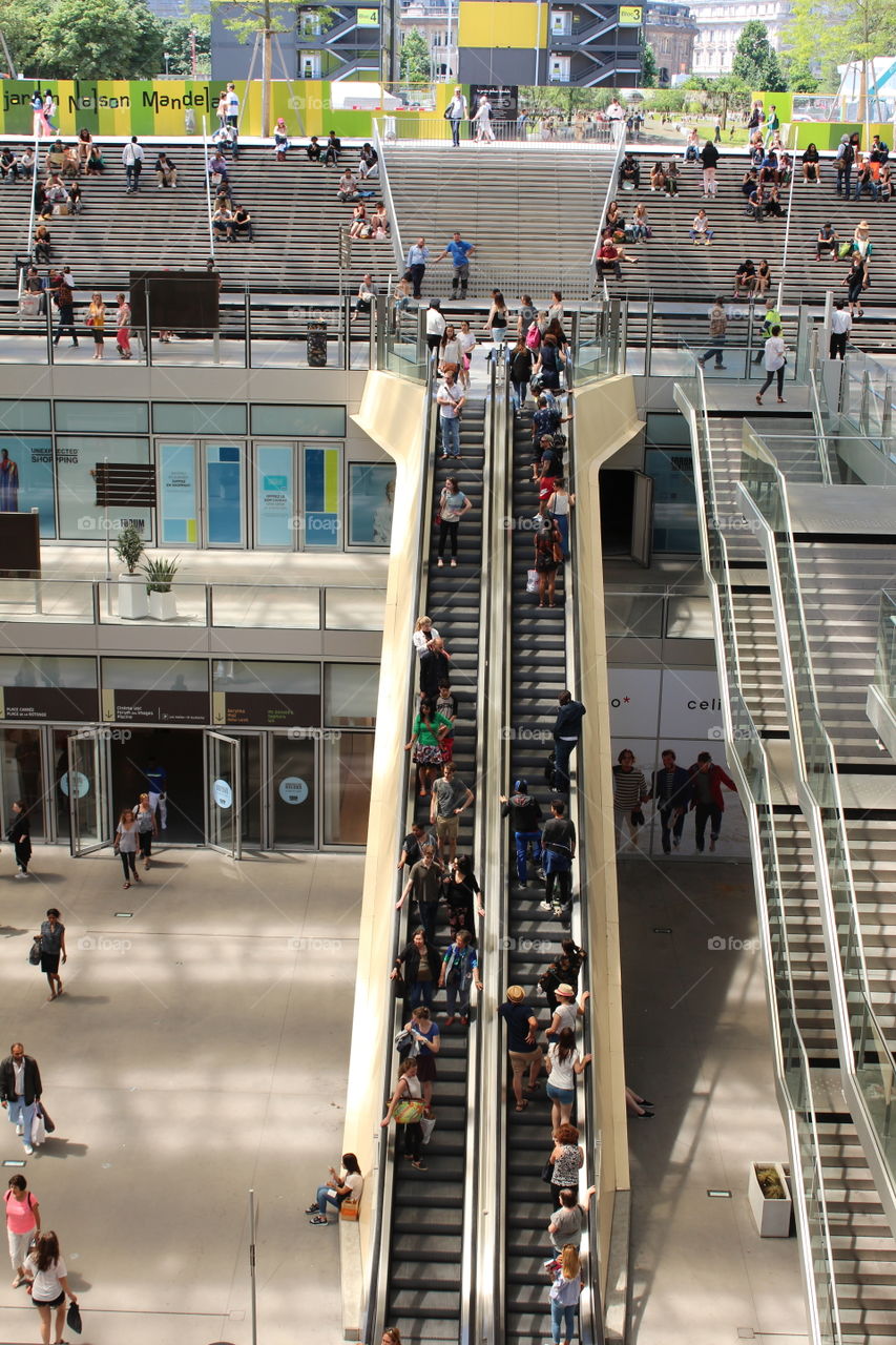 A view of people on escalators in an open air shopping and business center in Paris.