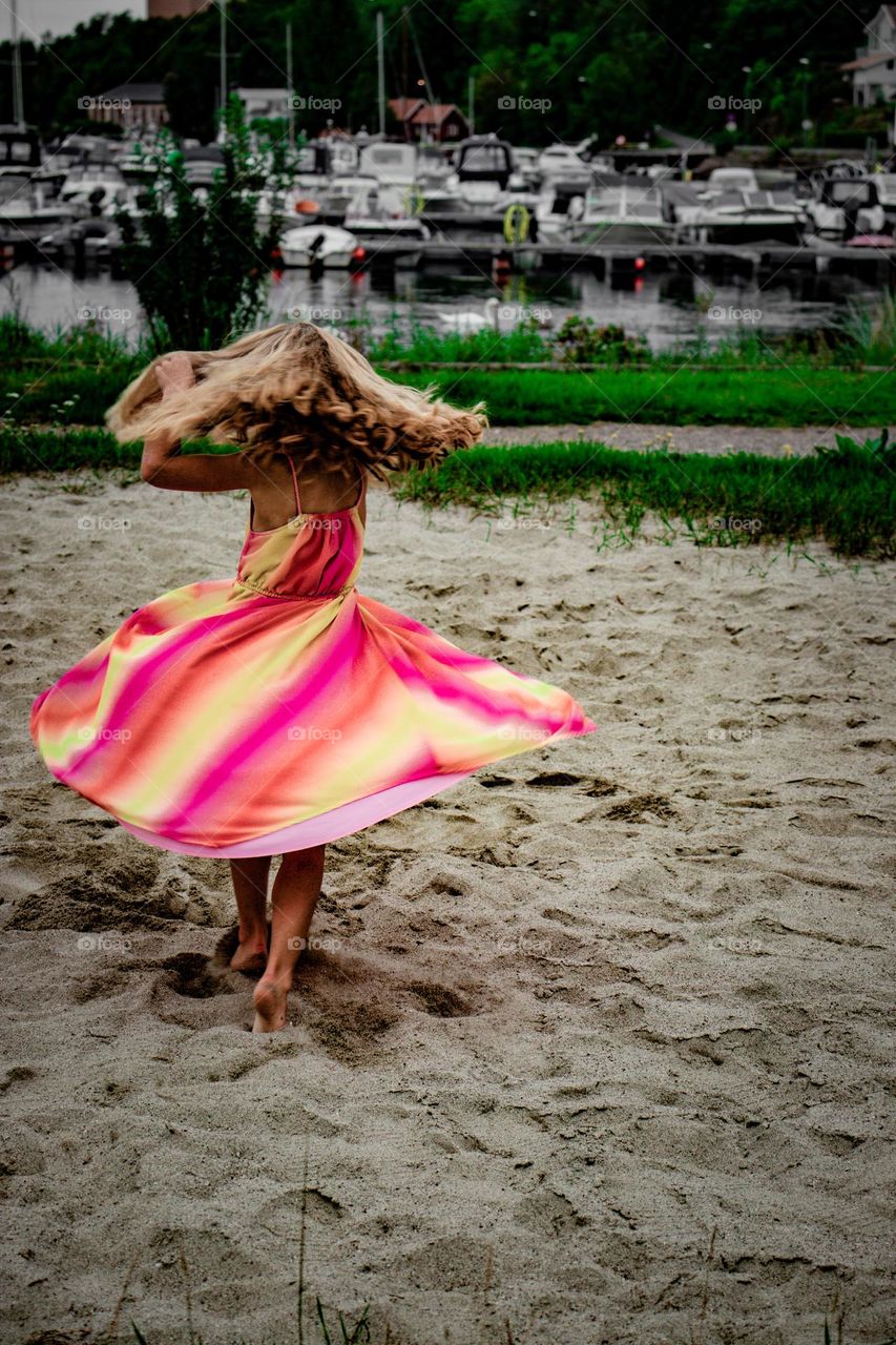 little girl dance in the sun at the beach with the colorful dres,its so fun.  ,since she didnt see me.