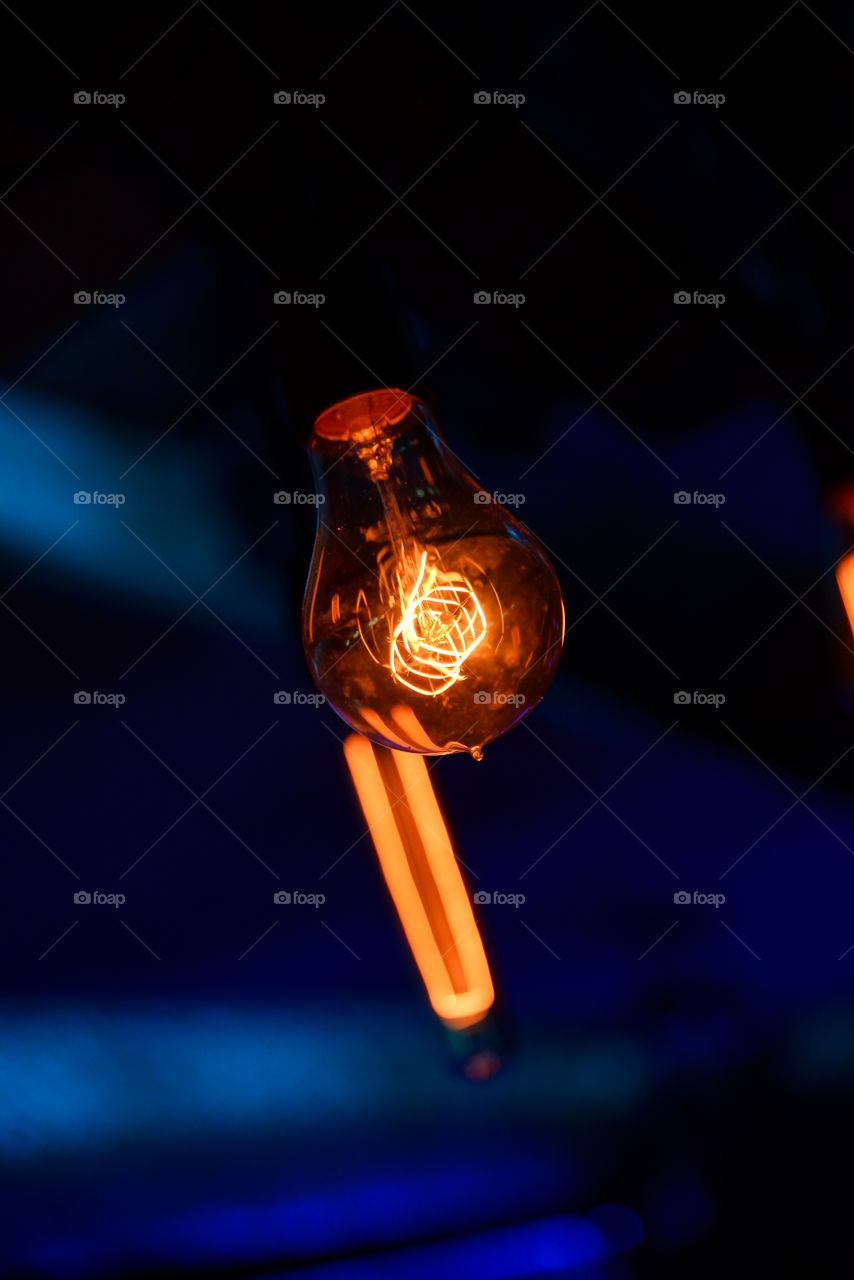 Beautiful glowing round bulb tungsten lamp, heated filament light. incandescent illumination on dark background