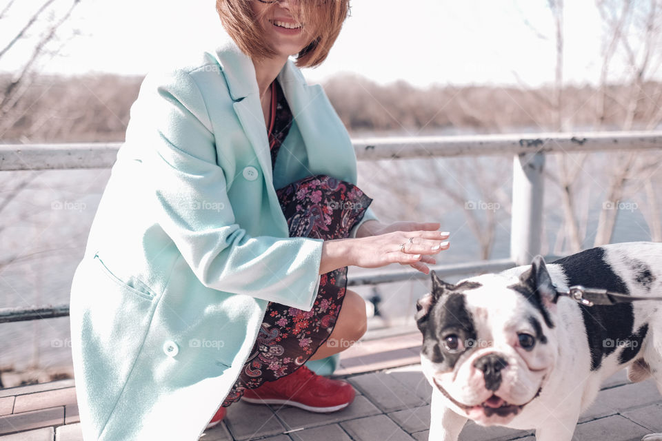 Smiling woman walking with dog in spring