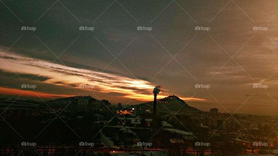 View of industry emitting smoke at sunset